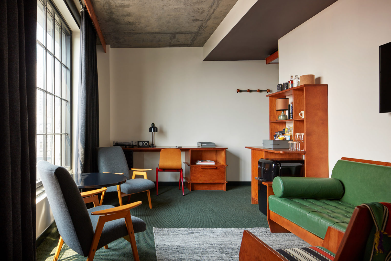 A living area with a desk for work tucked into the corner and a minibar featuring snacks, beverages and other essentials