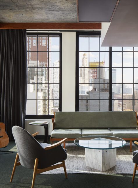 Spacious living space with multiple chairs and a sofa with windows on multiple walls providing sweeping city views
