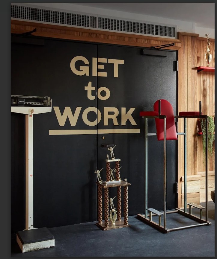 a photo of a gym with equipment that includes dip and leg raise standing machine and manual sliding scale. And a sign that reads, 