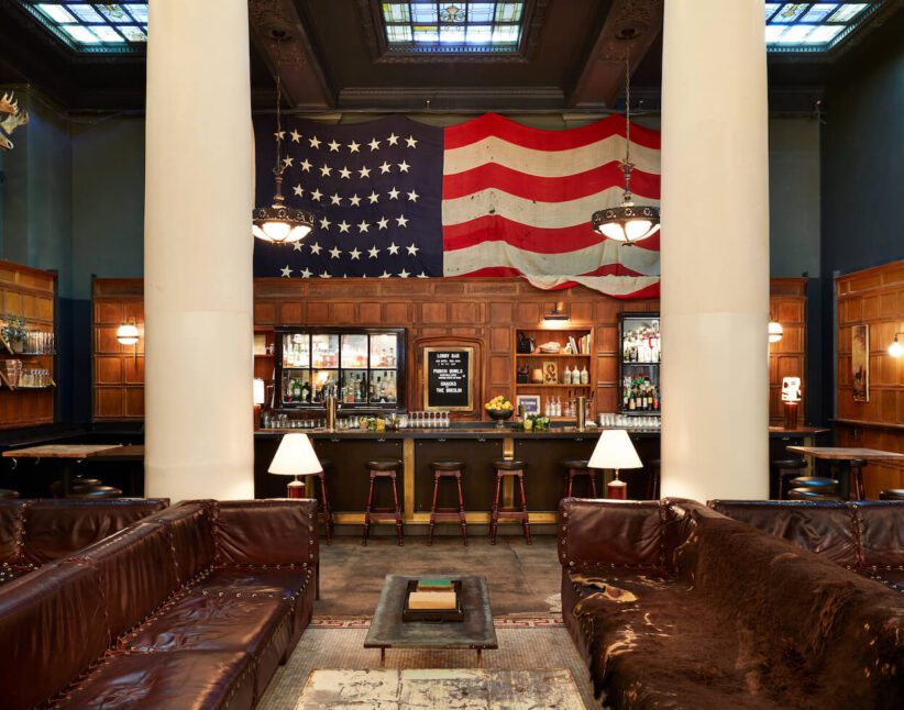 a lobby with mosaic tile featuring a large American flag framed by two white floor to ceiling pillars