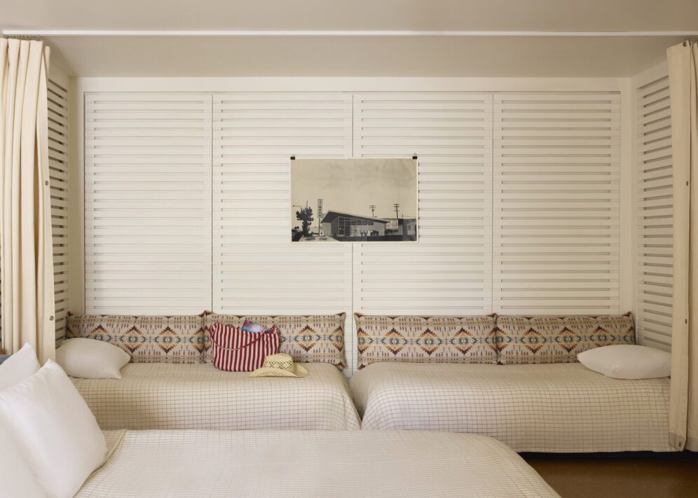 Two twin beds face each other against a wall, and a curtain sits in front of them to provide privacy