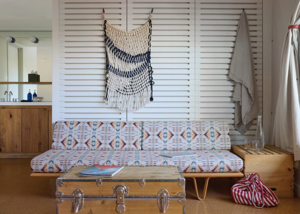 An ornate couch sits close to the floor with a coffee table with magazine for light reading